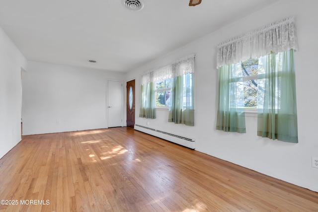 unfurnished room featuring visible vents, a baseboard heating unit, and light wood-type flooring