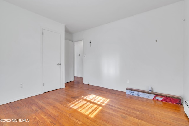 empty room featuring a baseboard heating unit and wood finished floors