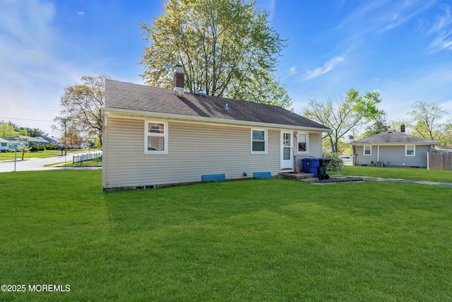 rear view of property featuring a yard and a chimney