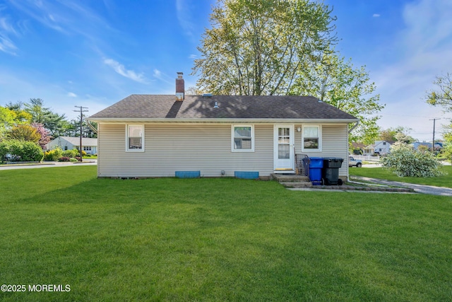 back of property featuring a lawn, a chimney, and a shingled roof