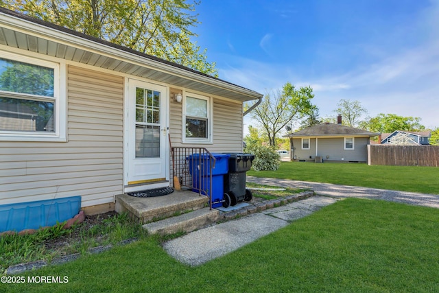 property entrance featuring fence and a yard