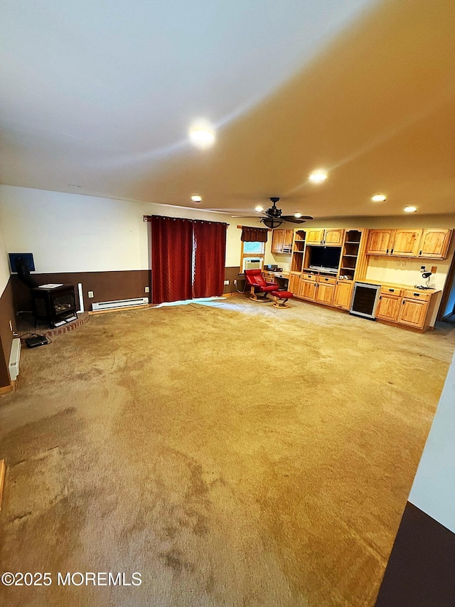 living room featuring carpet floors, a wood stove, ceiling fan, recessed lighting, and a baseboard heating unit