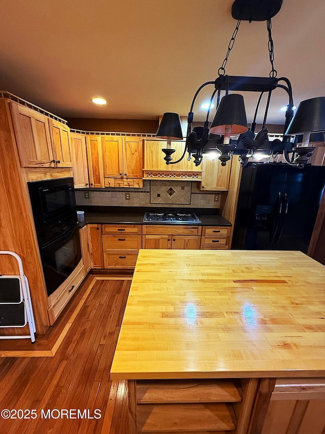 kitchen with dark wood-style flooring, a chandelier, wooden counters, tasteful backsplash, and black appliances