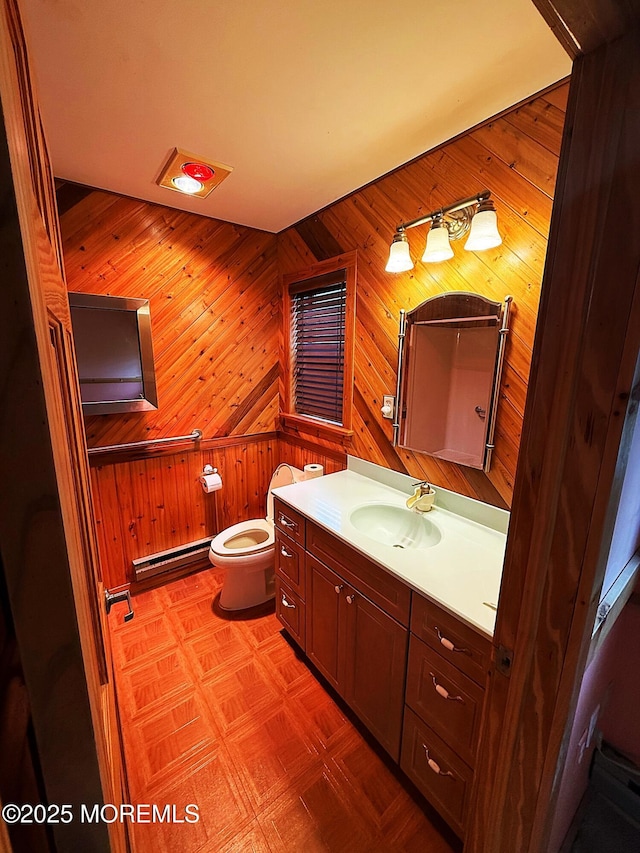 bathroom with vanity, a baseboard radiator, toilet, and wood walls