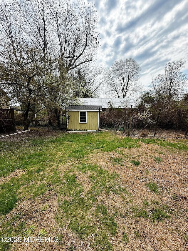 view of yard featuring fence, an outbuilding, and a storage unit