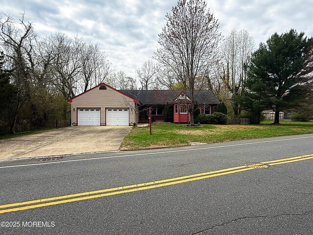 ranch-style house featuring concrete driveway, an attached garage, fence, and a front lawn
