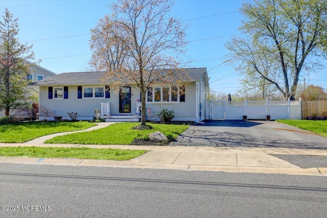 ranch-style home with driveway, fence, and a front yard