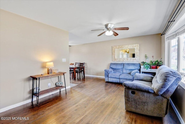 living room with baseboards, a ceiling fan, and wood finished floors