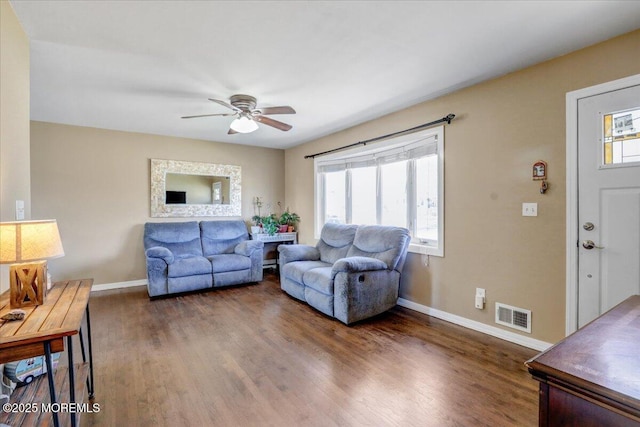 living room with wood finished floors, visible vents, baseboards, and ceiling fan