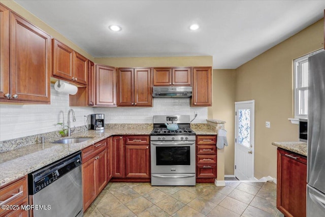 kitchen featuring a sink, appliances with stainless steel finishes, backsplash, baseboards, and under cabinet range hood