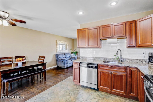 kitchen featuring a ceiling fan, a sink, backsplash, appliances with stainless steel finishes, and light stone countertops