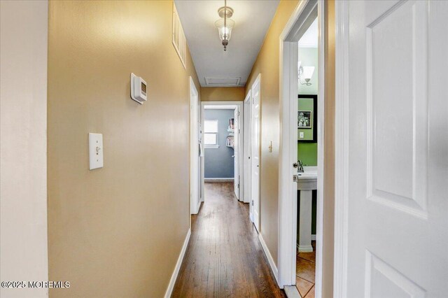 hall featuring attic access, baseboards, and dark wood-style floors