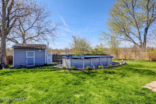 view of yard featuring fence, a fenced in pool, an outdoor structure, and a storage shed