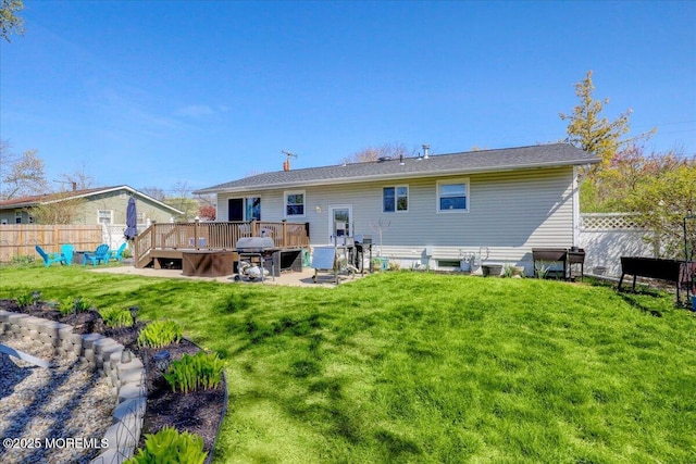 back of property with a wooden deck, a lawn, a patio, and fence
