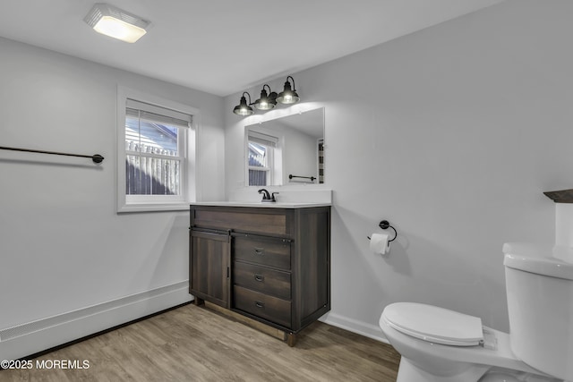 bathroom featuring baseboards, wood finished floors, toilet, and vanity