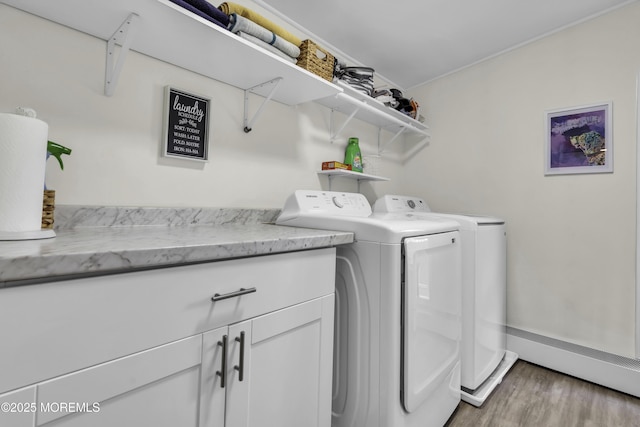 washroom featuring light wood-type flooring, baseboards, washer and dryer, and cabinet space