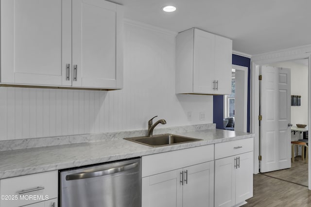 kitchen with stainless steel dishwasher, white cabinetry, wood finished floors, and a sink