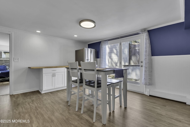 dining room with baseboard heating, a wealth of natural light, and wood finished floors
