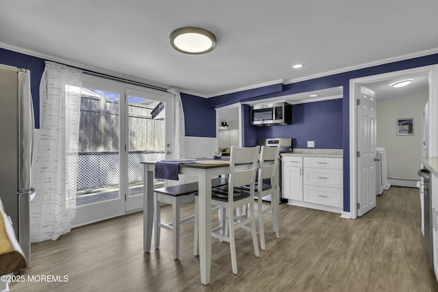 dining space with wood finished floors and ornamental molding