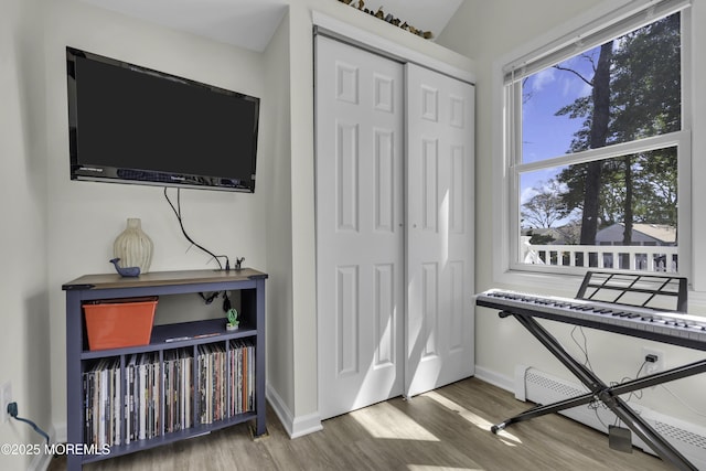 sitting room with a baseboard radiator, baseboards, and wood finished floors