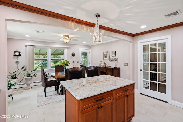 kitchen with light stone countertops, decorative light fixtures, ornamental molding, ceiling fan, and brown cabinets