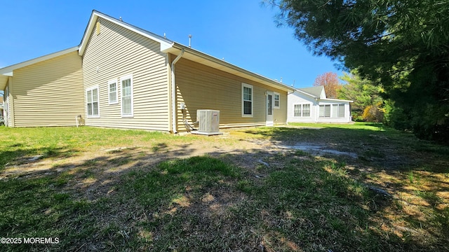 back of house featuring central air condition unit and a lawn