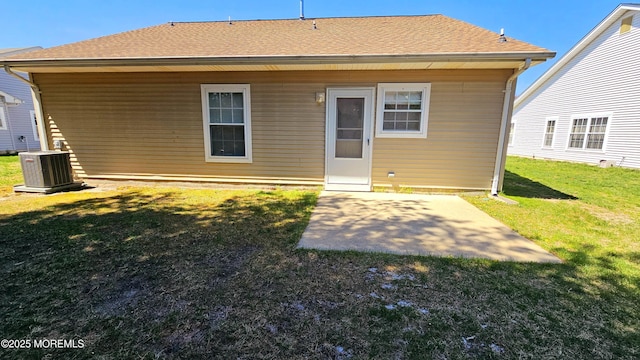 rear view of property with central AC unit, roof with shingles, a yard, and a patio