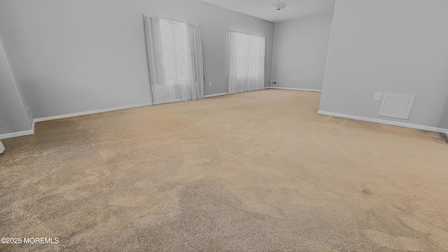 carpeted spare room featuring baseboards and visible vents