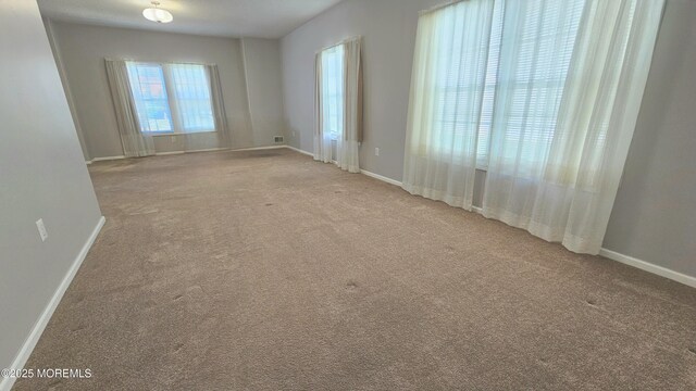 unfurnished room with baseboards and carpet flooring