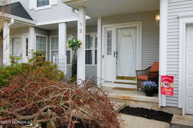 view of exterior entry featuring roof with shingles and a porch