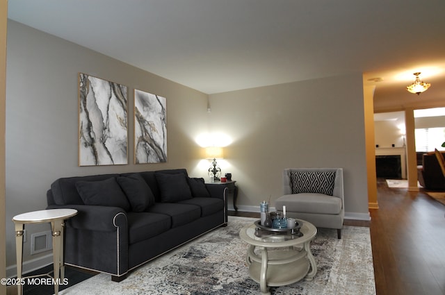 living area with visible vents, baseboards, and wood finished floors