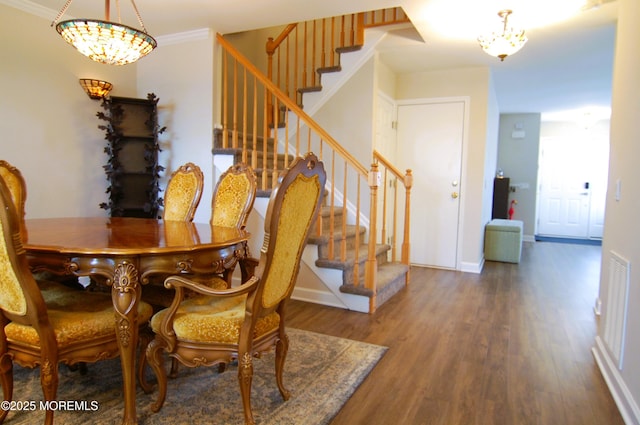 dining space with baseboards, stairs, wood finished floors, and a notable chandelier