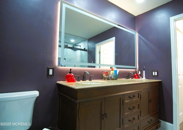 bathroom featuring double vanity, toilet, a sink, and a shower with shower door