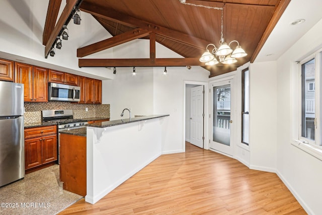 650 Front St, Union Beach, NJ 07735 - kitchen featuring an inviting chandelier, rail lighting, a peninsula, brown cabinetry, and appliances with stainless steel finishes