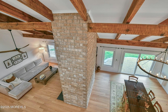 living area featuring beam ceiling, wood finished floors, and ceiling fan with notable chandelier