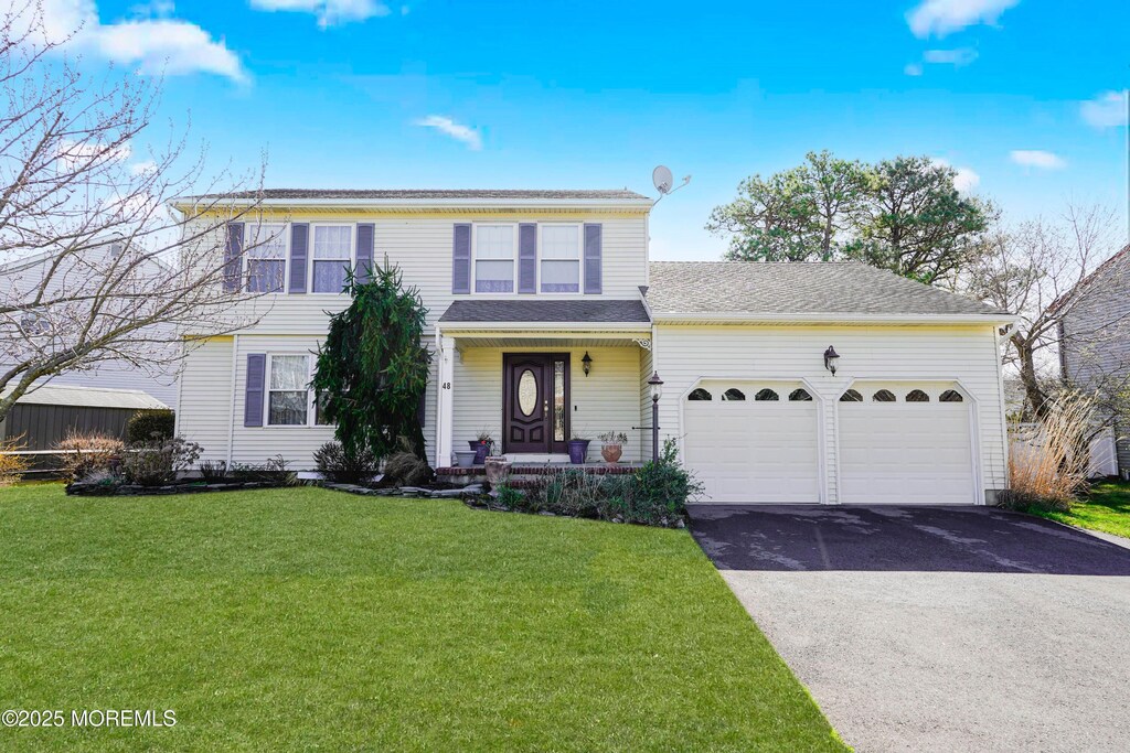 traditional-style house with a front lawn, driveway, and a garage