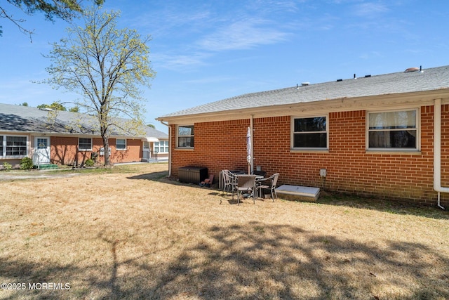 rear view of property featuring a lawn and brick siding