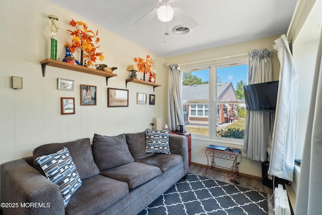 living room featuring baseboards, wood finished floors, visible vents, and ceiling fan