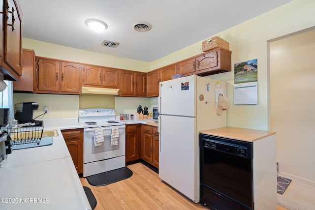 kitchen with visible vents, white appliances, brown cabinets, light countertops, and under cabinet range hood