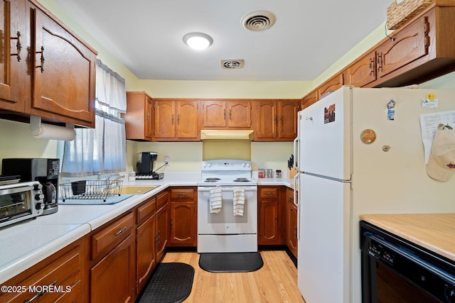 kitchen with light wood finished floors, light countertops, visible vents, white appliances, and brown cabinetry