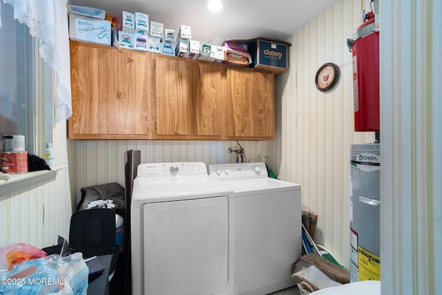 laundry room with cabinet space, washer and clothes dryer, wallpapered walls, and electric water heater