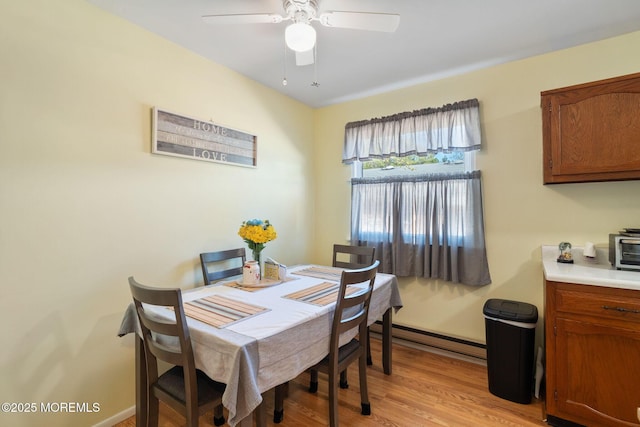 dining area with light wood-style flooring, baseboard heating, and ceiling fan