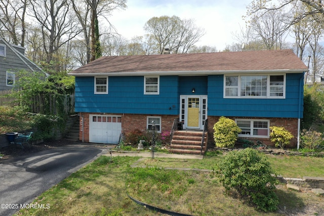 split foyer home featuring brick siding, a garage, and driveway