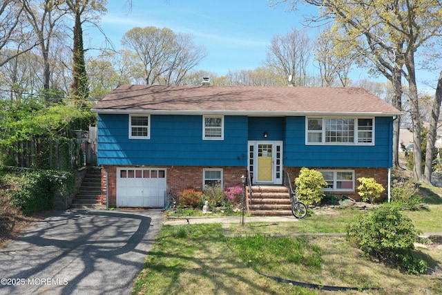 bi-level home with brick siding, a garage, driveway, and a shingled roof