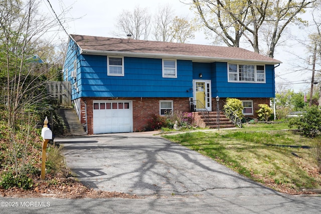 bi-level home with brick siding, driveway, and a garage