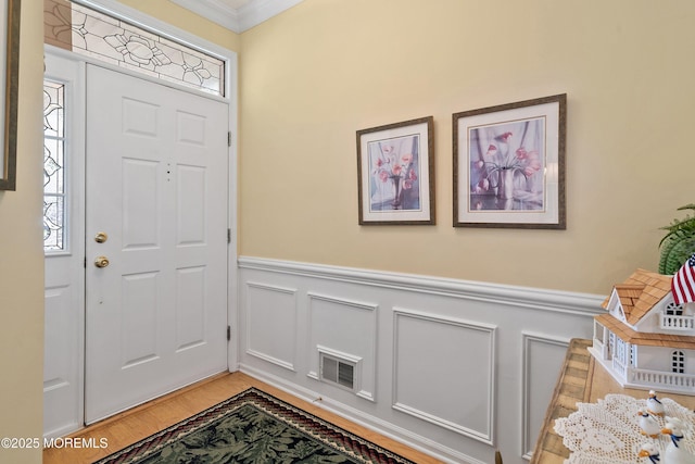 1507 Primrose Pl, Manasquan, NJ 08736 - entrance foyer with ornamental molding, a wainscoted wall, light wood-style flooring, and a decorative wall