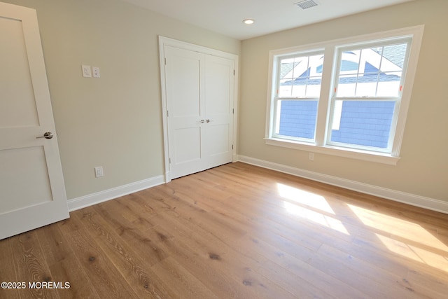 unfurnished bedroom with baseboards, wood finished floors, recessed lighting, and a closet