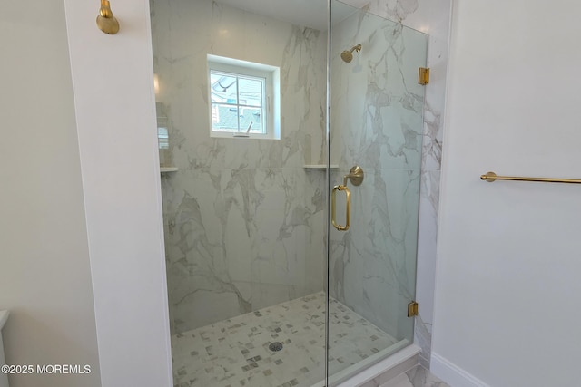 full bath featuring a marble finish shower, marble look tile flooring, and baseboards