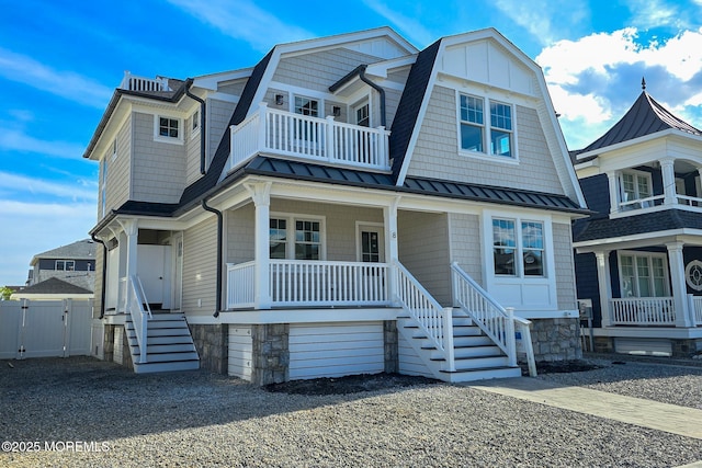 shingle-style home featuring a standing seam roof, covered porch, metal roof, a gambrel roof, and a gate