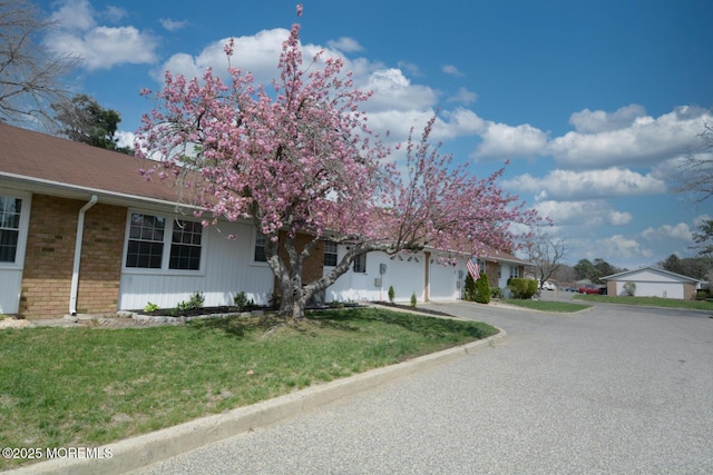 view of front of property featuring a garage, driveway, a front yard, and brick siding